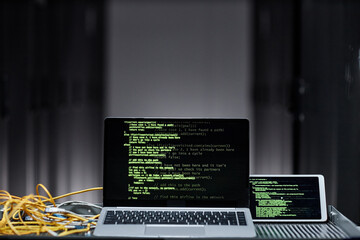 Minimal background image of laptop computer with green code lines on screen in server room, data...