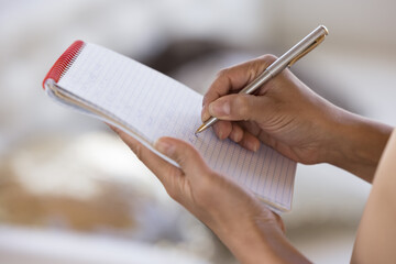 Woman writing on paper, using copybook, pen, making draft, accidently planning tasks. Waitress taking order, writing in notebook. Close up of female hands, cropped shot