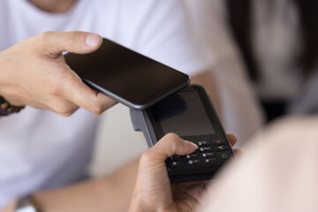 Male hand holding smartphone, applying camera to payment terminal blank screen, paying bill, purchase, service, using bank financial application for contactless connection