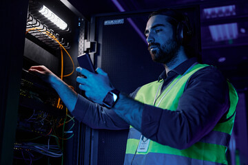 Close up of black man as network technician using control panel while setting up server in data...