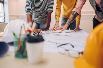 Multiracial team of architects having a meeting while using blueprints