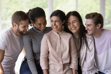 Excited cheerful multiethnic friends sitting close, chatting, laughing, feeling joy, enjoying...
