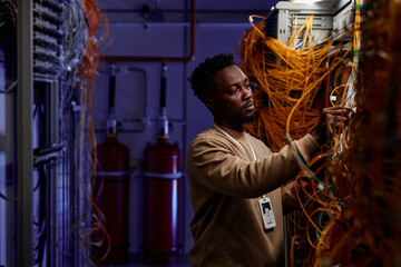 Side view portrait of black young man as system administrator working with server in neon light, copy space