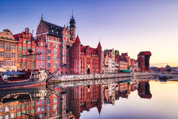 Fototapeta na wymiar Illuminated Gdansk Old Town with Calm Motlawa River at Sunrise, Poland