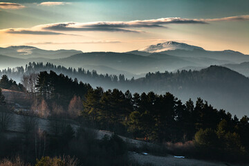 Mglisty poranny krajobraz ośnieżonych połonin z widokiem gór na horyzoncie oraz górskich zamglonych lasów, Bieszczady, Polska