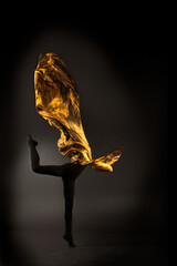 ballerina with golden fabric on a black background © Maestro7