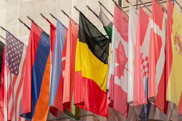 National flags of different countries hang from the facade of the building.