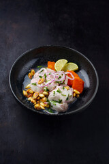Traditional Peruvian gourmet ceviche sea bass filet piece with sweet potatoes and cancha marinated and served in lime sauce as close-up in a modern design bowl