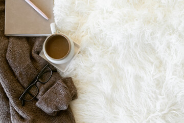 Styled Fashion Image. Dark Brown Sweater with Coffee Mug, Black Glasses, and Leather Bound Notebook. Social Media Image with Negative Copy Space. Casual Fall Fashion. Hygge Season.