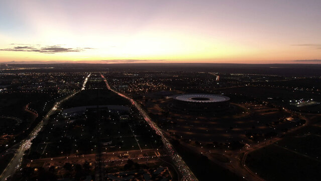 Aerial view of the monumental axis of the capital of Brazil at dusk, showing the Man&eacute; Garrincha stadium and a view of the skyline of Brasilia, Federal District