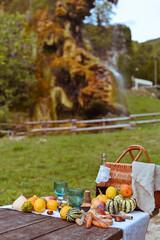 picnic in autumn park. Food, drinks, picnic basket on a wooden table in the garden. Cozy lunch atmosphere. Pumpkin, pie and wine on the table. High quality vertical photo