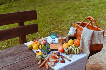 picnic in autumn park. Food, drinks, picnic basket on a wooden table in the garden. Cozy lunch atmosphere. Pumpkin, pie and wine on the table. High quality above photo