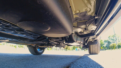 View of the car by auto mechanic from below. Automobile exhaust system and hoses. All wheel drive...