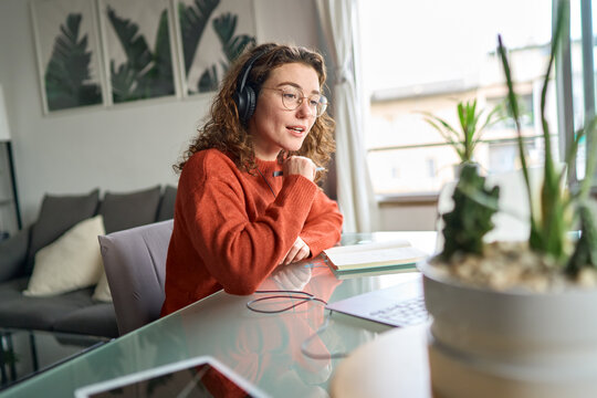 Young Woman Elearning Watching Webinar Using Computer At Home. Female Student Or Remote Worker Wearing Headphones Learning Online On Laptop Distance Working, Having Conference Meeting, Virtual Class.