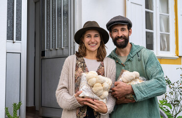 happy young couple of farmers smiling to camera and holding production blocks of lion mane...