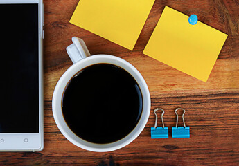 Workspace with phone with copy space, office supplies, and coffee cup on wooden  background. Top view with copy space, flat lay.