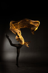 ballerina with golden fabric on a black background