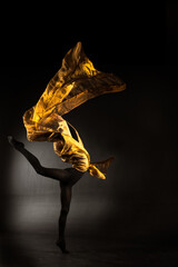 ballerina with golden fabric on a black background © Maestro7