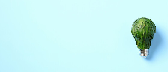 Light bulb, adorned with plant leaves on blue background. Banner design for eco-friendly product promotion, energy conservation awareness campaigns, and nature conservation projects.