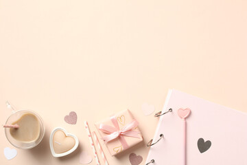 Valentine's Day flat lay composition with gift box, coffee cup, candles, paper photo album, hearts on beige background.