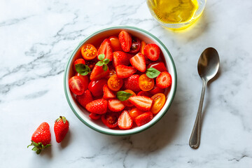 Portion of strawberry, tomato cherry and basil leaves salad