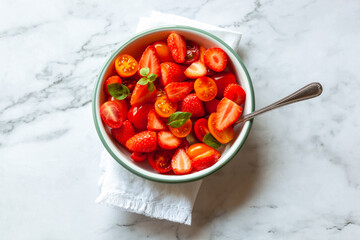 Portion of strawberry, tomato cherry and basil leaves salad