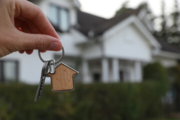 Woman holding house keys outdoors, closeup with space for text. Real estate agent
