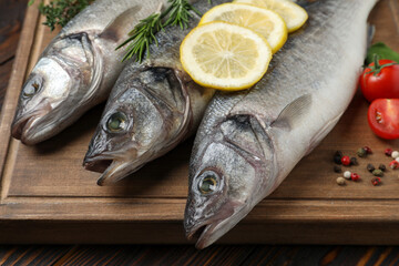 Sea bass fish and ingredients on wooden table, closeup
