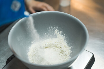 Professional baker measuring flour into white bowl to prepare cupcake batter. Baking process. Dry ingredients. Horizontal indoor shot. High quality photo