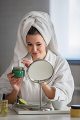 Obraz na płótnie Canvas Portrait of a young beautiful woman wearing a bathrobe at home. doing her daily skincare routine with natural cosmetics