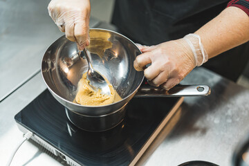 Unrecognisable professional baked preaping base for caramel apple dessert in silver bowl. Baking process. Advanced dessert-making. Horizontal indoor shot. High quality photo