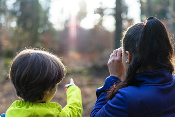 Mother and son looking through binoculars in forest