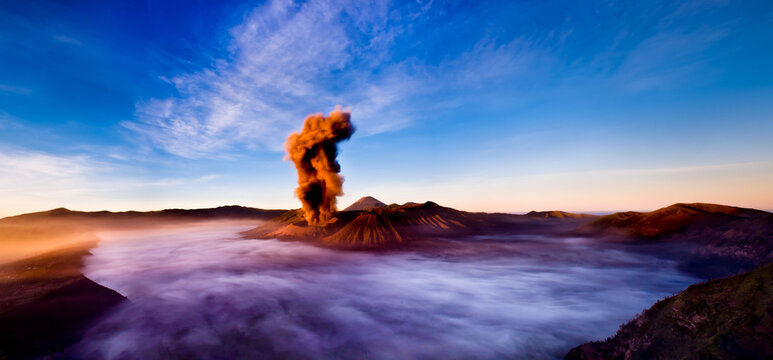 Mt. Bromo volcano erupting in the early morning with fog filling the area around it.
