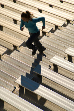 A young woman runs up a set of bleacher stairs during training.
