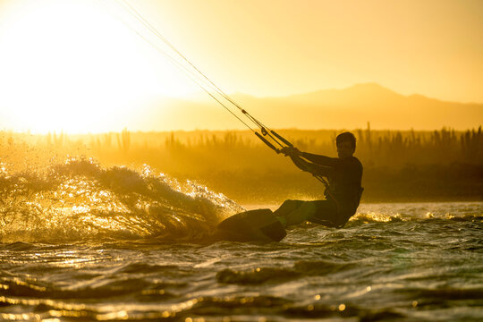 Young male athlete kiteboarding at sunset in La Ventana, Baja California, Mexico