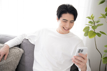 スマホを見ながら素敵な笑顔になる男性　コピースペースあり アップ