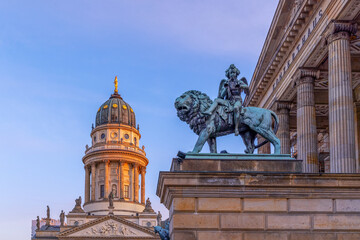 Löwenskulptur mit Engel am Konzerthaus und Kuppel des Französischen Doms auf dem Gendarmenmarkt...