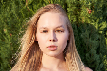 Close up of young woman face, natural blonde hair, has no makeup, looking at camera.