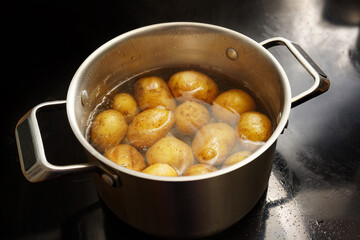 Potatoes with peel in a stainless steel pot with boiling water on the stove, healthy cooking...