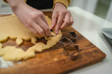 Top and side view of mother and daughter preparing gingerbread cookies with rolling pin in their kitchen in different shapes heart and stars 