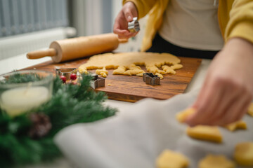 Top and side view of mother and daughter preparing gingerbread cookies with rolling pin in their kitchen in different shapes heart and stars 