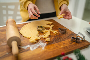 Top and side view of mother and daughter preparing gingerbread cookies with rolling pin in their kitchen in different shapes heart and stars 