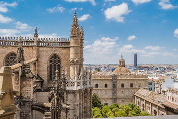 Gothic style with typical decoration in the Cathedral of Seville with windows and flying buttresses, in the background dome and courtyard of orange trees, SPAIN