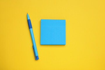 Paper notes and pen on yellow background, flat lay