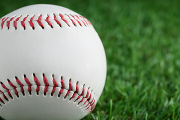 Baseball ball on green grass, closeup with space for text. Sports game