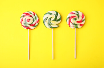 Colorful lollipops on yellow background, flat lay