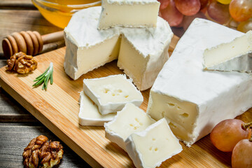 Brie cheese with grapes, nuts and honey on the Board.