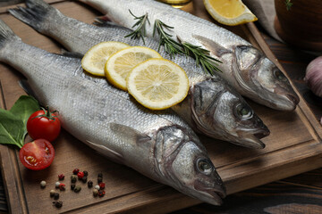 Sea bass fish and ingredients on wooden table, closeup