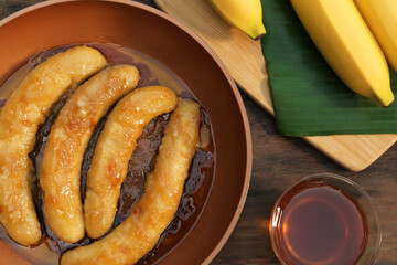 Delicious fresh and fried bananas with rum on wooden table, flat lay