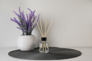 Aromatic reed air freshener and lavender flowers on white table. Space for text
